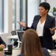 Businesswoman leading a team meeting in a modern office setting.